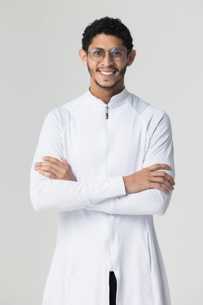 Dr. Davi Teixeira de jaleco branco, em pé e de braços cruzados, sorrindo